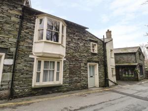 una antigua casa de piedra con una ventana blanca en una calle en Rowan Cottage, en Grasmere