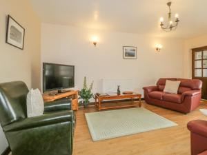 ein Wohnzimmer mit einem Sofa und einem TV in der Unterkunft Stonegarth Cottage in Penrith