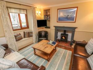 a living room with a couch and a table and a fireplace at Puddle Duck Cottage in Spark Bridge