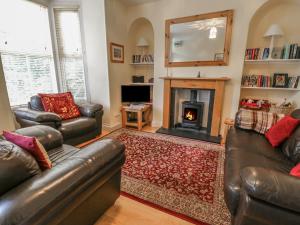 uma sala de estar com dois sofás de couro e uma lareira em Lamb Cottage em Windermere