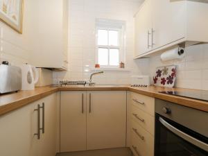 uma cozinha com armários brancos e um lavatório em Siskin em Keswick