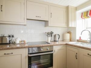 a kitchen with white cabinets and a sink at Blacksmiths Cottage in Pooley Bridge