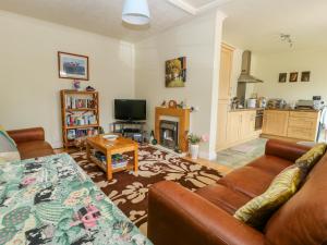 un salon avec un canapé et une télévision dans l'établissement Richmond Cottage, à Malton