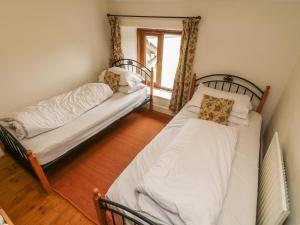 two beds sitting in a room with a window at Puddle Duck Cottage in Spark Bridge