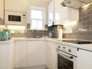 a white kitchen with white cabinets and a sink at Fox's Den in Keswick