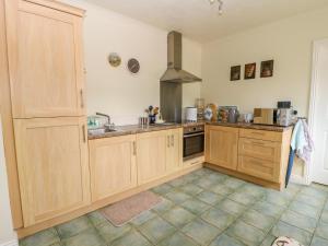 une grande cuisine avec des placards en bois et un évier dans l'établissement Richmond Cottage, à Malton