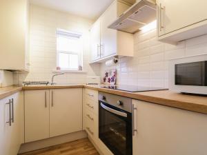 a kitchen with white cabinets and a sink and a microwave at Siskin in Keswick