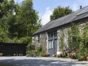 una casa de campo de piedra con flores delante en The Stone Barn Cottage, en Holne