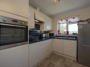 a kitchen with white cabinets and stainless steel appliances at Exe View in Dawlish