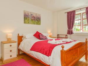 a bedroom with a large bed with a red blanket at Ludgate Cottage in Bovey Tracey