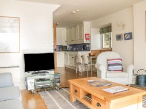 ein Wohnzimmer mit einem TV und einem Tisch in der Unterkunft Sandridge Boathouse in Stoke Gabriel