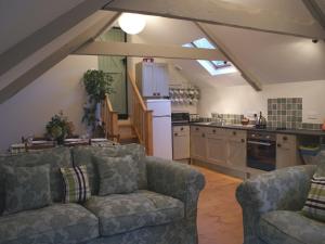 a living room with a couch and a kitchen at The Stone Barn Cottage in Holne