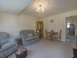 uma sala de estar com um sofá, uma mesa e cadeiras em Exe View em Dawlish