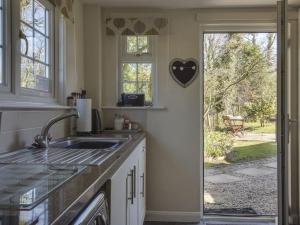 une cuisine avec un évier et une porte donnant sur une cour. dans l'établissement Little Week Cottage, à Bridestowe