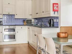 a kitchen with white cabinets and a table with chairs at Sandridge Boathouse in Stoke Gabriel