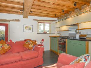 a living room with a red couch and a kitchen at The Bakehouse in Gidleigh