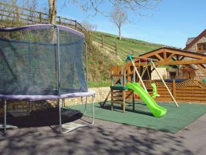 um parque infantil com um escorrega verde e um baloiço em The Barn em Southleigh