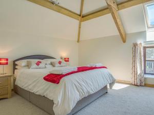 a bedroom with a large bed with a red blanket on it at Orchard Barn in Virginstow
