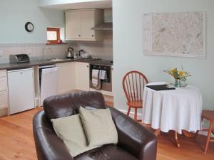a living room with a couch and a table in a kitchen at 1 Shippen Cottages in Cotleigh