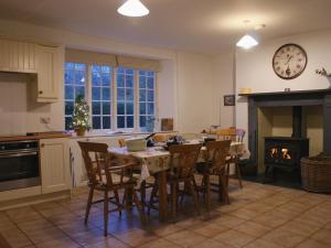 a kitchen with a table and chairs and a fireplace at Heyden Cottage in Minehead