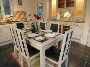 a white kitchen with a table with plates and chairs at Glenview in Lynton