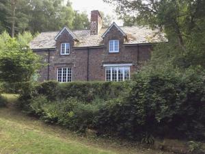 an old brick house is behind a hedge at Heyden Cottage in Minehead +8 photos