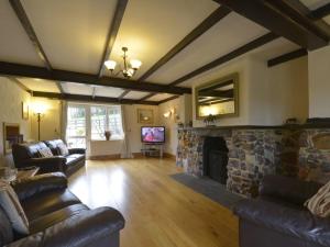 a living room with couches and a stone fireplace at Lower Wadden Farmhouse and Annexe in Southleigh