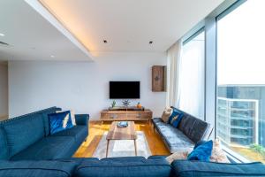a living room with blue couches and a tv at Brand new 3 Bedroom apartment in Bluewaters island in Dubai