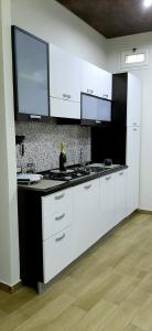 a kitchen with white cabinets and a black counter top at Castello Apartment Deluxe in Sciacca