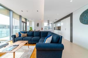 a living room with a blue couch and a table at Brand new 3 Bedroom apartment in Bluewaters island in Dubai