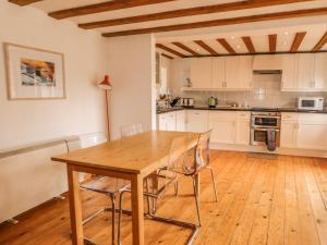 cocina con mesa de madera y sillas en Abbey Cross Barn, en Hemyock