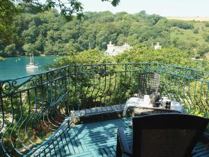 a balcony with a table and chairs and a body of water at Galanda Treetops in Newton Ferrers