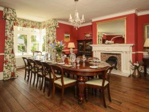 a dining room with a table and chairs and a fireplace at Abbots Manor in Honiton