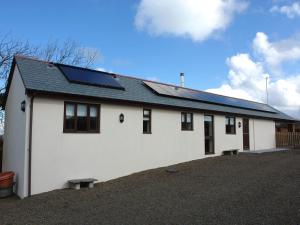 a white house with solar panels on it at Barn View in Welcombe