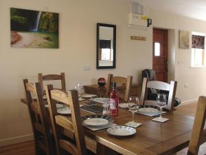 a dining room table with chairs and a bottle of wine at Barn View in Welcombe