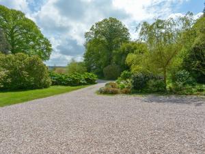 a gravel driveway in a garden with trees at The Barn in Aveton Gifford