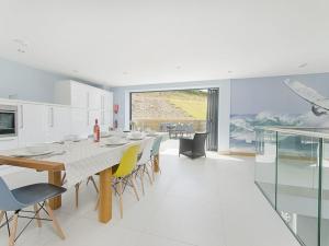 a white kitchen with a long dining table and chairs at 5 Beachdown in Bigbury