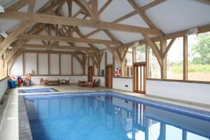 a swimming pool in a building with wooden beams at The Hay Barn in Halwell