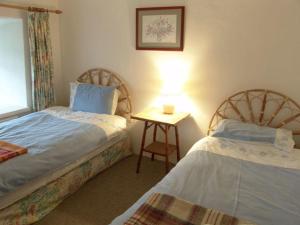 1 dormitorio con 2 camas y mesa con lámpara en Tom en Bodmin
