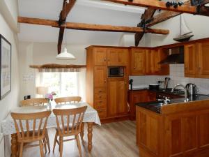 una cocina con armarios de madera y una mesa con sillas. en Cherry Tree Cottage en Noss Mayo