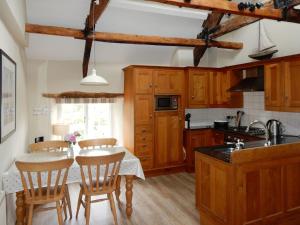 een keuken met houten kasten en een tafel met stoelen bij Cherry Tree Cottage in Noss Mayo