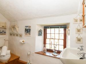 ein Badezimmer mit Waschbecken und Toilette und einem Fenster in der Unterkunft Uphill Cottage in Saint Ervan + 22 Fotos