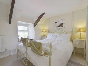 een slaapkamer met een wit bed en een raam bij Mays Cottage in Saint Issey