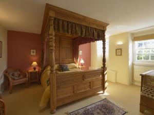 a bedroom with a large wooden canopy bed at Grooms Cottage in Saint Minver