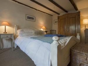 um quarto com uma grande cama branca e uma cadeira em Cherry Tree Cottage em Noss Mayo