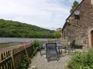 a table and chairs outside of a building next to a river at The Boat House in Lerryn