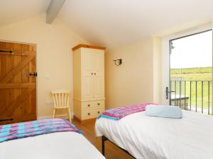 a bedroom with two beds and a large window at Dozmary Pool Barn in Temple
