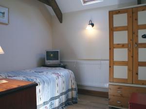 1 dormitorio con 1 cama y escritorio con TV en The Clock House en Harford