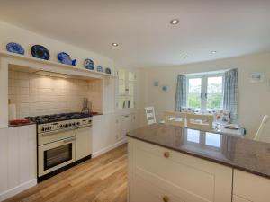 a kitchen with white cabinets and a stove top oven at Junket Cottage in Newton Ferrers