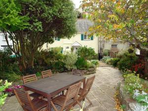 een houten tafel en stoelen in de tuin bij Cherry Tree Cottage in Noss Mayo +5 foto's